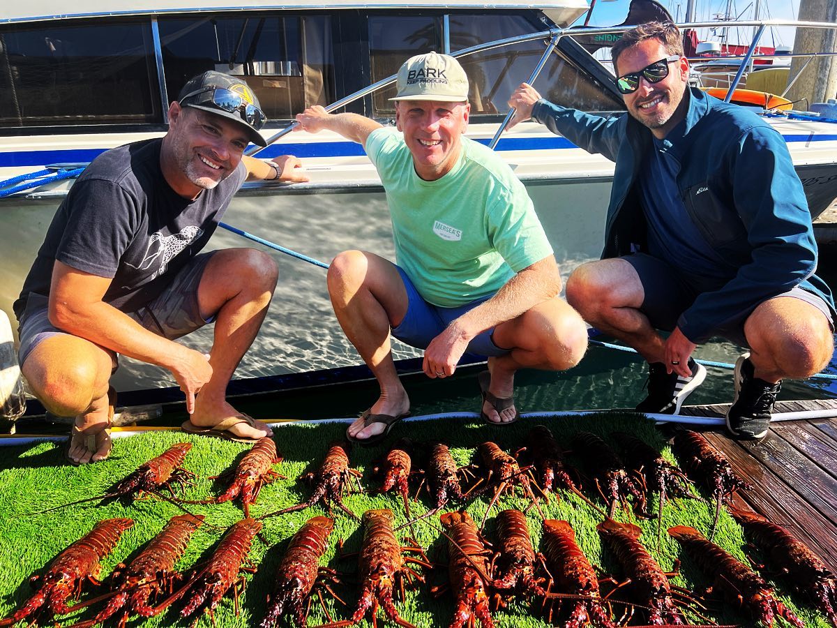 Three guests on the dock with their lobster haul after a day trip